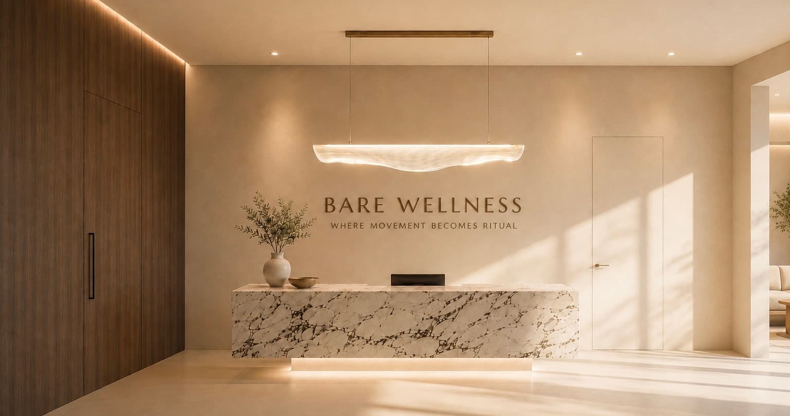 The Bare Wellness reception: a marble desk beneath an alabaster pendant, the wordmark on a warm plaster wall